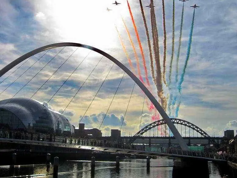 The Red Arrows trailing coloured smoke over the Gateshead Millennium Bridge and the Tyne