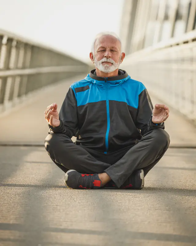 An older man sitting calmly with his eyes closed, taking a moment to settle