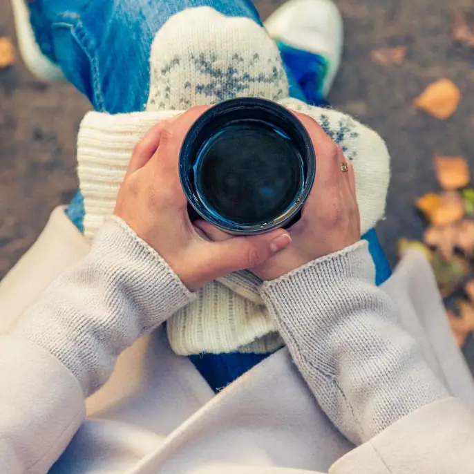 Hands in a knitted jumper holding a warm mug