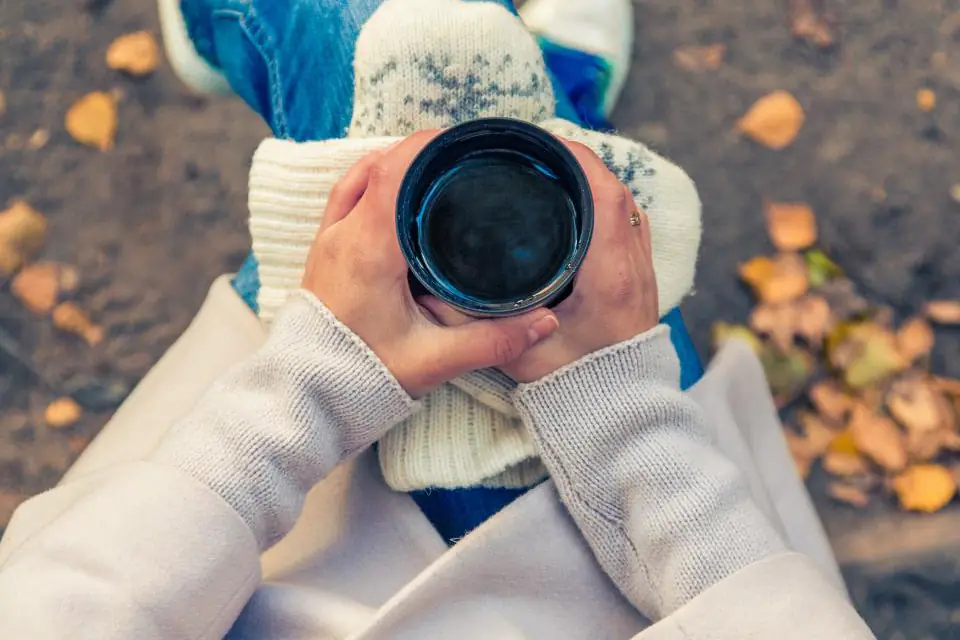 Hands in a knitted jumper holding a warm mug