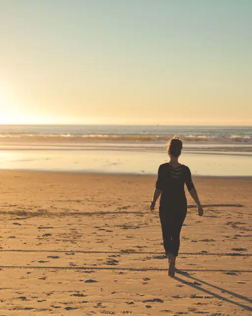 A person walking along a beach at sunrise